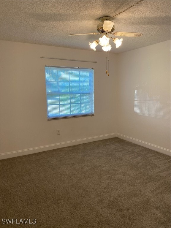 empty room with a textured ceiling, dark carpet, and ceiling fan