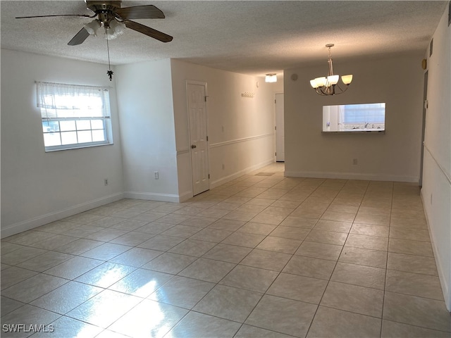 tiled empty room with ceiling fan with notable chandelier and a textured ceiling