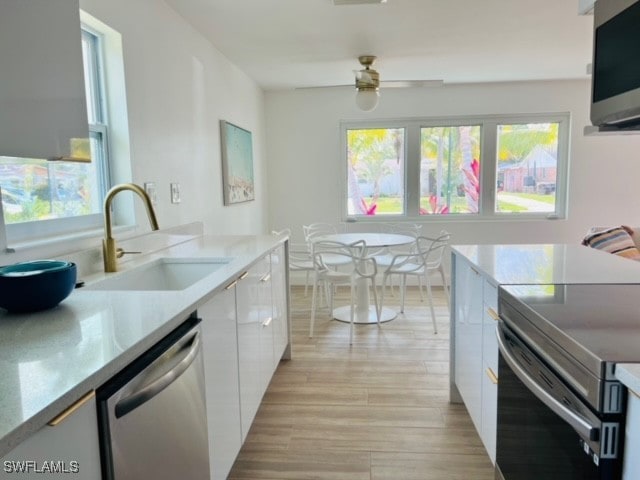 kitchen with white cabinets, sink, ceiling fan, appliances with stainless steel finishes, and light hardwood / wood-style floors