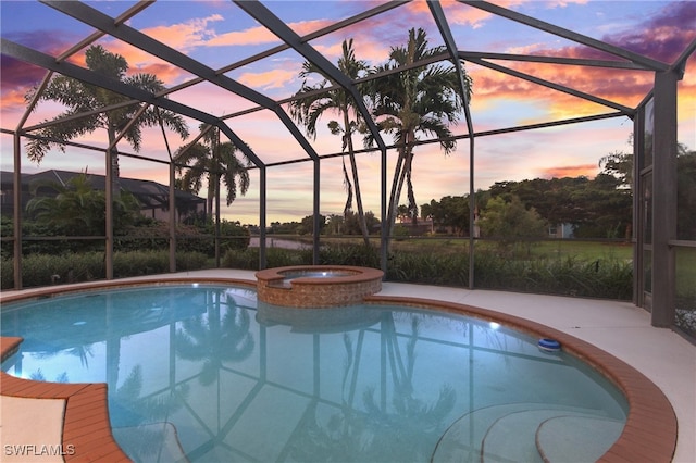 pool at dusk featuring an in ground hot tub and glass enclosure