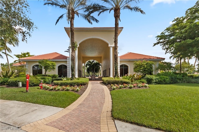 exterior space with stucco siding, a front yard, and a tiled roof