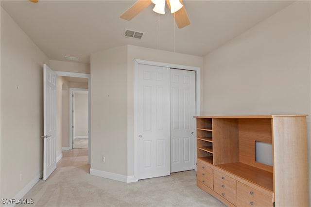 unfurnished bedroom featuring ceiling fan, a closet, and light carpet