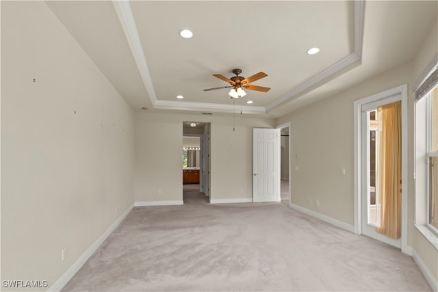 unfurnished bedroom featuring light carpet, a tray ceiling, ornamental molding, and ensuite bathroom