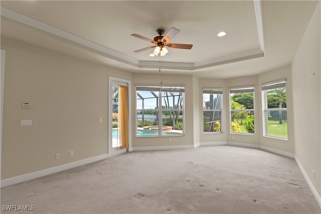 empty room featuring carpet flooring, a raised ceiling, baseboards, and ornamental molding