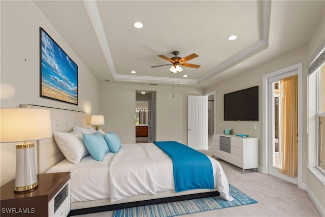 bedroom with light colored carpet, ornamental molding, a tray ceiling, and connected bathroom