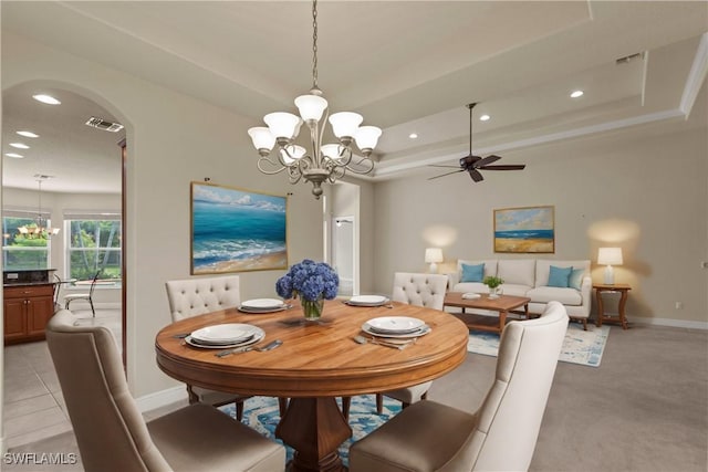 dining area featuring baseboards, recessed lighting, ceiling fan with notable chandelier, arched walkways, and a raised ceiling