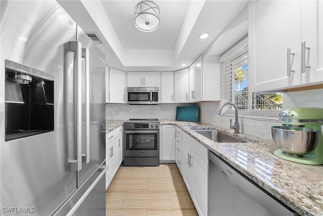 kitchen with white cabinetry, sink, light stone counters, and appliances with stainless steel finishes