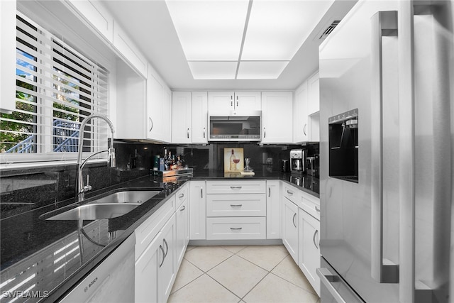 kitchen with decorative backsplash, appliances with stainless steel finishes, dark stone counters, sink, and white cabinets