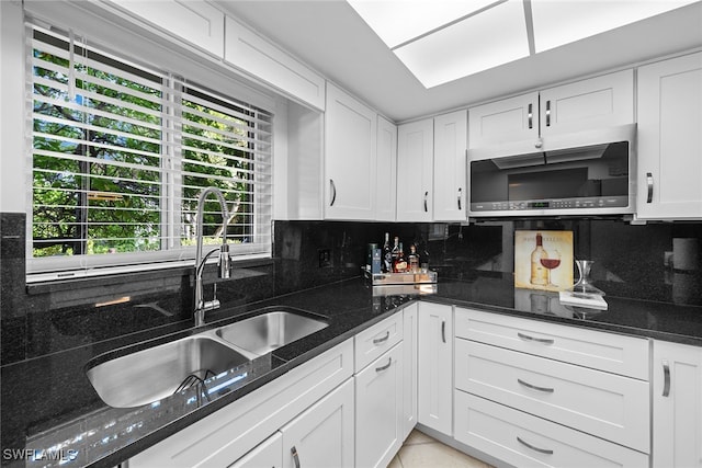 kitchen featuring decorative backsplash, white cabinetry, and dark stone counters