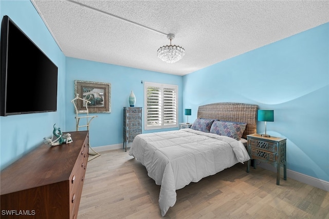 bedroom with a textured ceiling and light hardwood / wood-style flooring