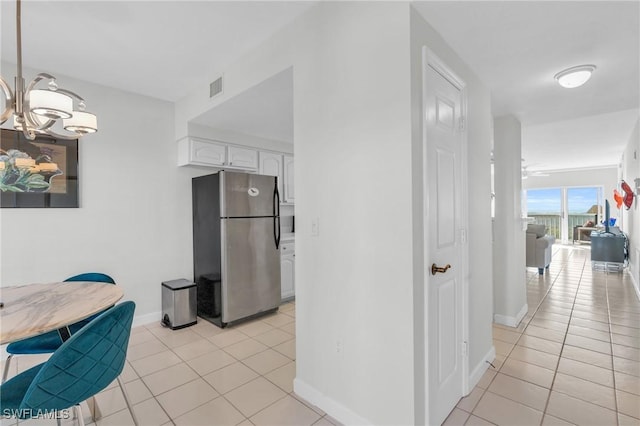 kitchen featuring decorative light fixtures, white cabinetry, light tile patterned floors, and stainless steel refrigerator