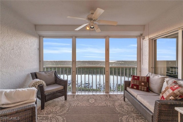 sunroom with ceiling fan, a wealth of natural light, and a water view