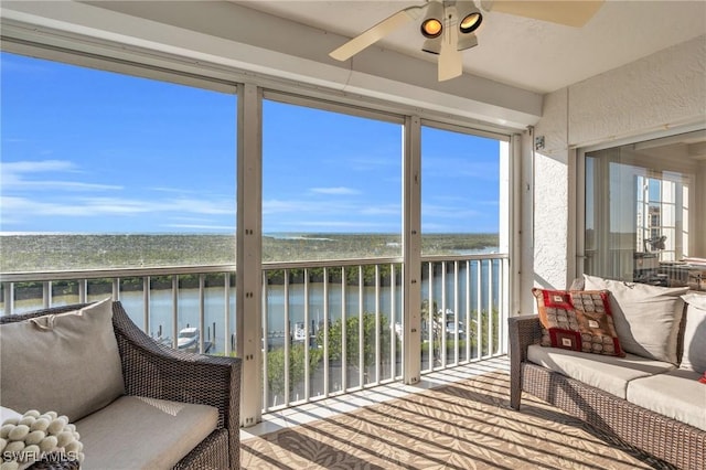 sunroom / solarium featuring ceiling fan and a water view