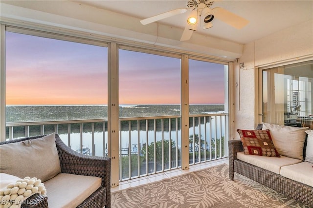 sunroom with a water view and ceiling fan