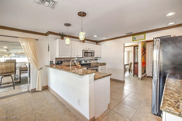 kitchen featuring kitchen peninsula, appliances with stainless steel finishes, dark stone countertops, white cabinets, and hanging light fixtures