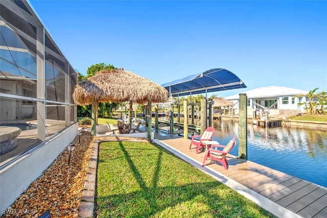 view of dock with a yard, a water view, and a lanai