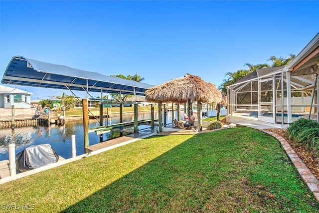 dock area with glass enclosure, a water view, and a yard