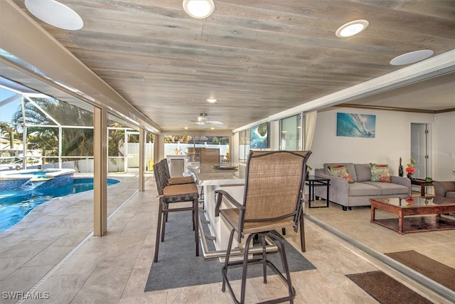 view of patio / terrace with outdoor lounge area, ceiling fan, exterior bar, and glass enclosure