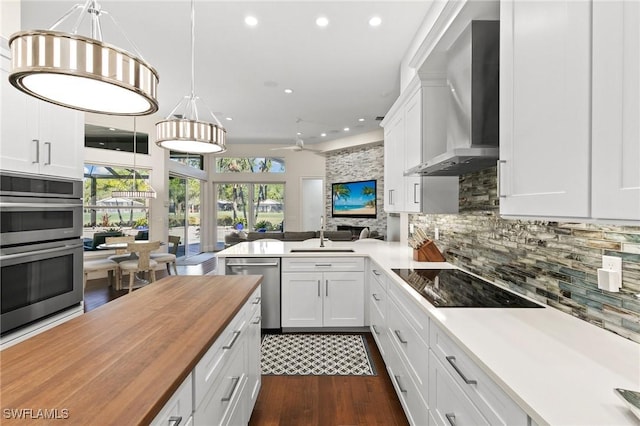 kitchen featuring white cabinetry, a wealth of natural light, and wall chimney exhaust hood