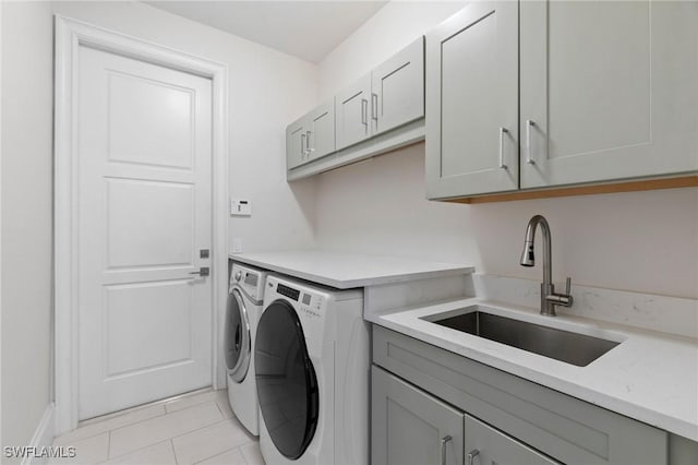 clothes washing area featuring cabinets, light tile patterned floors, washer and clothes dryer, and sink