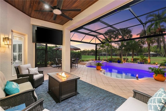 view of swimming pool featuring ceiling fan, a lanai, a patio, and an outdoor living space with a fire pit