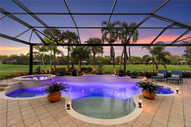 pool at dusk featuring an in ground hot tub, a patio, and glass enclosure