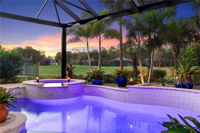 pool at dusk featuring an in ground hot tub and a yard