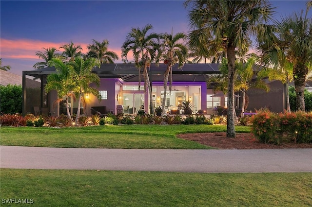 view of front of house with a lawn and glass enclosure