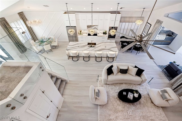 interior space featuring ceiling fan with notable chandelier and light wood-type flooring