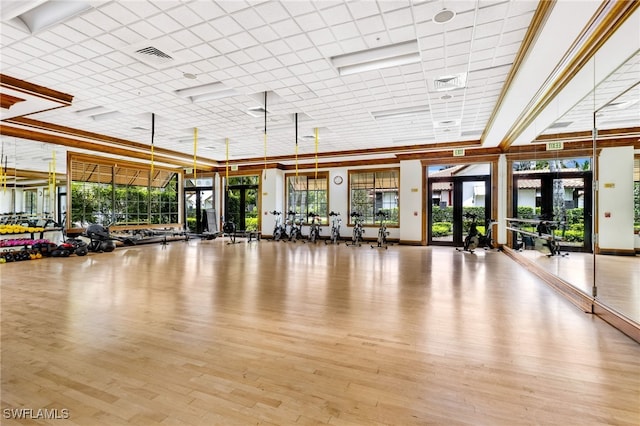 gym featuring french doors, light wood-type flooring, and crown molding