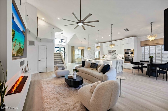 living room featuring ceiling fan, high vaulted ceiling, and light hardwood / wood-style flooring