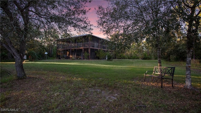 yard at dusk featuring a sunroom