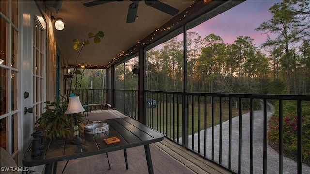 balcony at dusk featuring ceiling fan and a water view