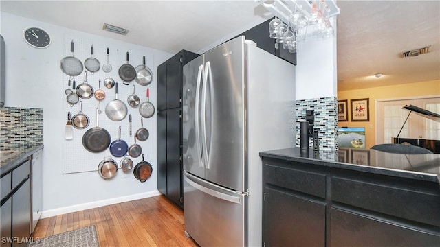 kitchen with decorative backsplash, stainless steel fridge, and light wood-type flooring