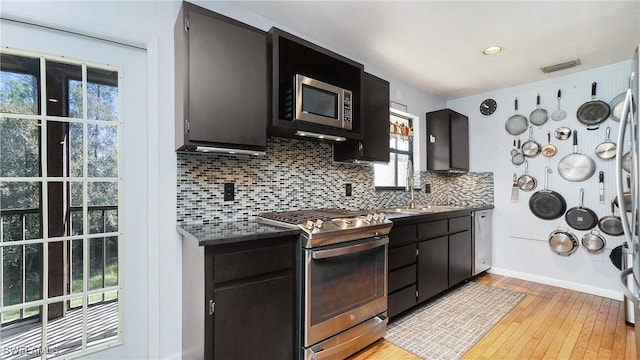 kitchen featuring tasteful backsplash, sink, light wood-type flooring, and appliances with stainless steel finishes