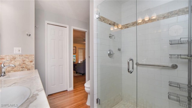 bathroom with hardwood / wood-style flooring, vanity, toilet, and a shower with shower door