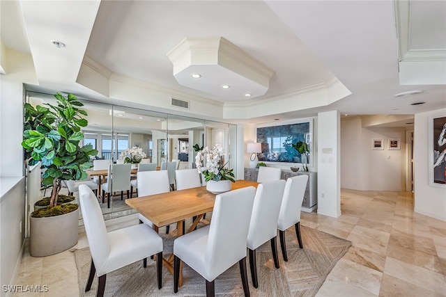 dining space with a tray ceiling and ornamental molding