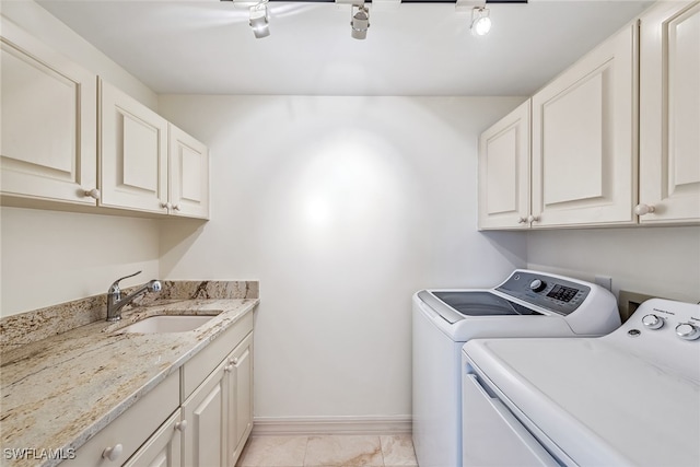 washroom with washing machine and clothes dryer, sink, rail lighting, and cabinets