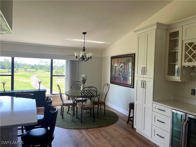 dining area featuring wine cooler, an inviting chandelier, vaulted ceiling, and hardwood / wood-style flooring