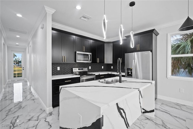 kitchen with crown molding, a wealth of natural light, a center island with sink, and stainless steel appliances