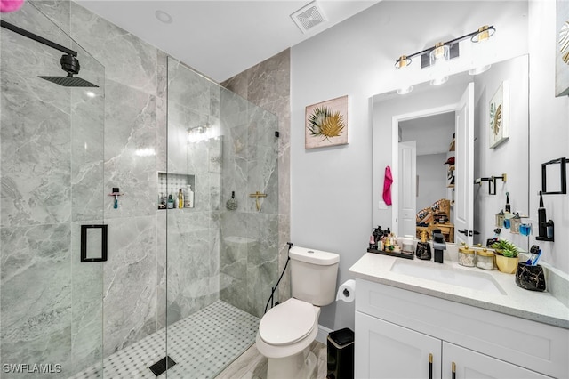 bathroom featuring a shower with door, vanity, and toilet