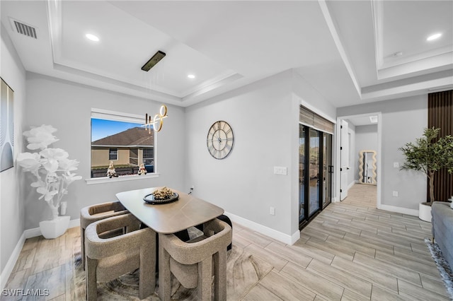 dining area featuring a raised ceiling, light wood-type flooring, and crown molding