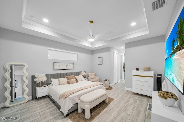 bedroom with light hardwood / wood-style floors, a raised ceiling, and ceiling fan