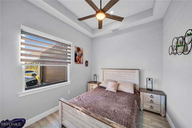 bedroom featuring hardwood / wood-style flooring, a raised ceiling, and ceiling fan