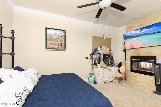 bedroom featuring carpet flooring, a tile fireplace, ceiling fan, and crown molding