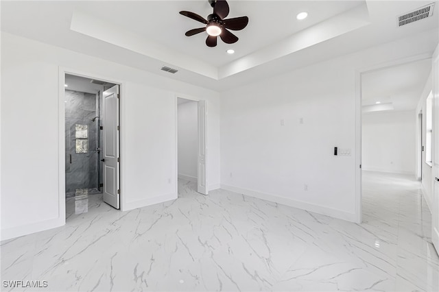 unfurnished bedroom with connected bathroom, a raised ceiling, and ceiling fan