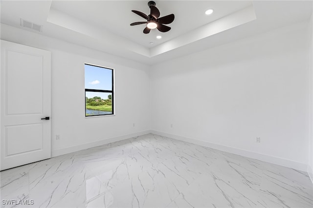 unfurnished room featuring a raised ceiling and ceiling fan