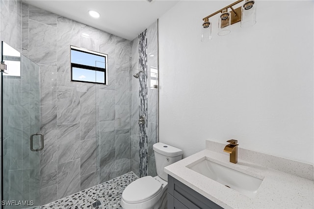 bathroom featuring vanity, a shower with shower door, and toilet