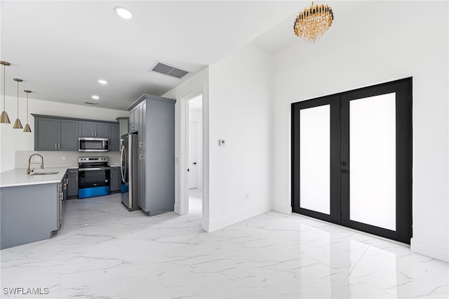 interior space with sink, an inviting chandelier, pendant lighting, gray cabinets, and appliances with stainless steel finishes