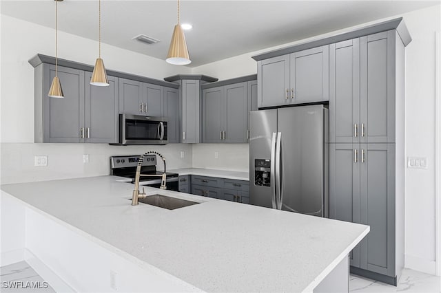 kitchen featuring gray cabinetry, decorative light fixtures, kitchen peninsula, and appliances with stainless steel finishes